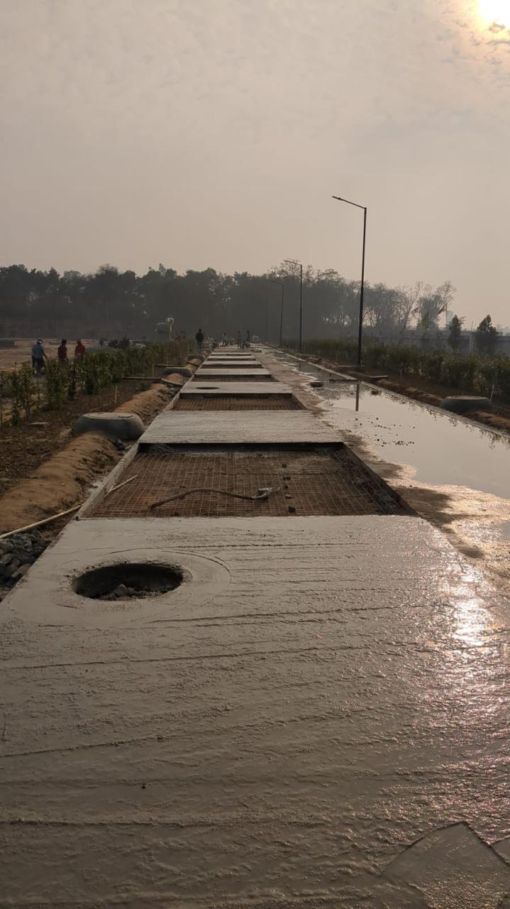 Concrete road being laid with steel mesh and manhole chambers at sunrise
