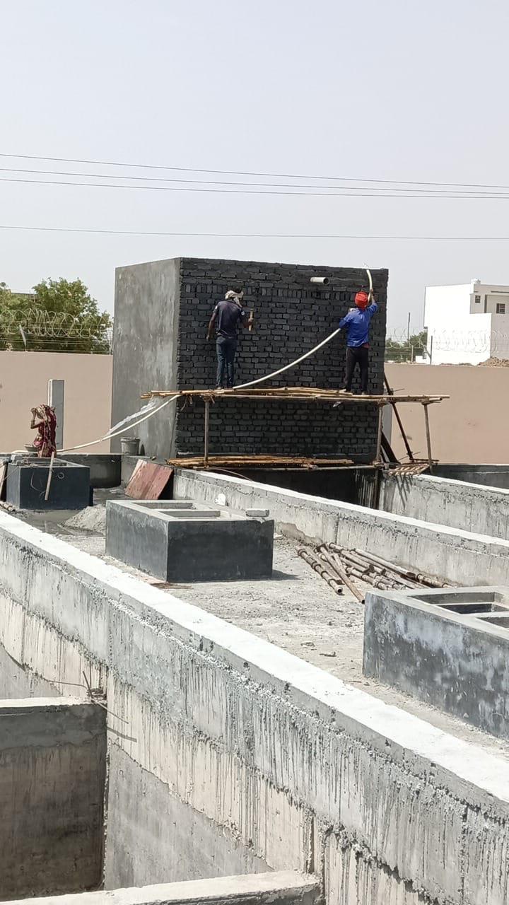 Masons building a brick water tank on a rooftop